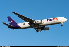 a fedex airplane is flying in the sky with it's landing gear down