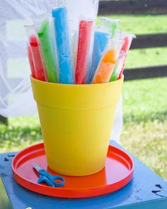 a yellow cup filled with plastic straws on top of a blue and red tray