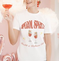 Aperol Spritz Themed Unisex T-Shirt *Size up for oversized look* Unisex heavy cotton tee. Basic staple of any wardrobe. No side seams mean there are no itchy interruptions under the arms. 100% cotton (fiber content may vary for different colors) Classic fit Tear-away label Runs true to size ... Aperol Spritz T-Shirt, Alcohol shirt, Funny shirt, Alcohol gift, Aperol Spritz gift, Gift for Aperol Spritz lover, Unisex tshirt, Gifts for her, Birthday gift ideas, Bachelorette party shirts, bachelorett White Crew Neck T-shirt For Party, Party T-shirt With Letter Print In Relaxed Fit, Graphic Tee For Party, White T-shirt For Spring Party, Relaxed Fit Cotton T-shirt For Party, White Cotton T-shirt For Party, Crew Neck Cotton T-shirt For Party, Cotton Crew Neck T-shirt For Party, White Graphic Print T-shirt For Party