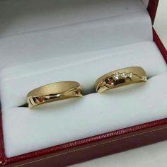 two yellow gold wedding rings in a red velvet ring box with white diamonds on them