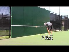 a man hitting a tennis ball with a racquet on a court in front of a fence