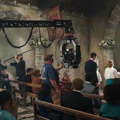 a group of people standing in front of pews at a church with cameras around them