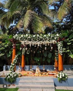 an outdoor wedding setup with flowers and greenery on the ground, surrounded by palm trees