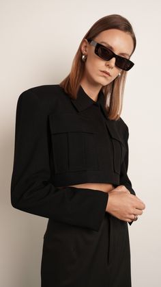 Our Clarice Crop Jacket is designed with a relaxed fit, cropped silhouette, and structured detailing. A pointed collar, enlarged flap pockets, and front button closure create a sleek, sophisticated look. Padded shoulders and lining add a layer of comfort. Style confidently with this polished jacket. Dry Clean Only Model is wearing XS XS body length 44cm Arm length 64cm Chest 107 cm S body length 45.5cm Arm length 64.5cm Chest 111cm M body length 47cm Arm length 65cm Chest 115cm Black Wool Blazer, Skirt Crop, Holiday Party Outfit, Off Black, Comfort Style, Lifestyle Shop, Blazer Dress, Wool Blazer, Blue Jacket