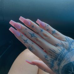 a woman's hand with pink nail polish and stars on it