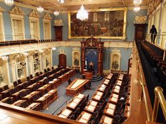 a large room with many chairs in it and an ornate painting on the wall above