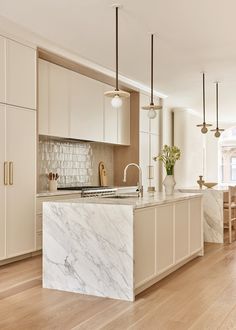 a kitchen with marble counter tops and white cabinets, along with wooden floors that have light colored wood flooring