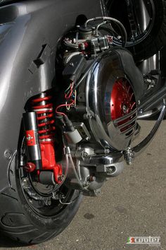 the front end of a motorcycle with red brake pads and chrome exhaust pipes on it