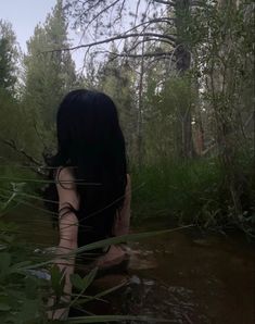 a woman is sitting in the water with her back to the camera