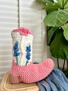 a knitted boot sitting on top of a wooden table next to a potted plant