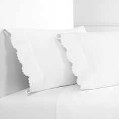 three white pillows on top of a bed next to each other with scalloped edges