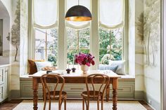 a dining room table with four chairs and a vase of flowers on top of it