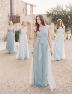 the bridesmaids are wearing blue dresses and one is standing in front of an old stone building