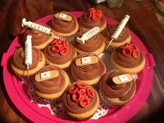 a pink plate topped with cupcakes covered in chocolate frosting and red icing