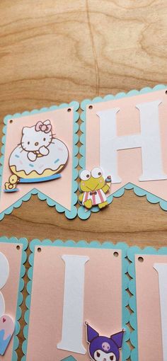 two hello kitty birthday cards on a table with the letters h and j cut out