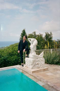 a man standing next to a statue near a pool