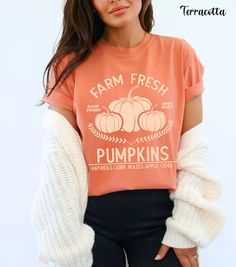 Embrace the autumn season with our Farm Fresh Pumpkins Shirt, featuring a charming design of three pumpkins with the words "Farm Fresh Pumpkins Hayrides, Corn Mazes, Apple Cider." Perfect for trips to the pumpkin patch, this pumpkin crewneck offers the cozy comfort of Comfort Colors. Ideal for any fall outing, this pumpkin patch shirt is a must-have in your collection of autumn tees. Whether you're sipping apple cider or enjoying a hayride, this fall crewneck provides both warmth and style. Add Cute Pre-shrunk Shirt For Fall, Orange Graphic Print T-shirt For Fall, Soft-washed Comfort Fit T-shirt For Fall, Soft-washed Comfortable T-shirt For Fall, Fall Cotton Shirt In Orange, Fall Cotton Tops With Letter Print, Fall Relaxed Fit T-shirt With Screen Print, Graphic Tee For Fall, Comfortable Graphic Tee For Fall