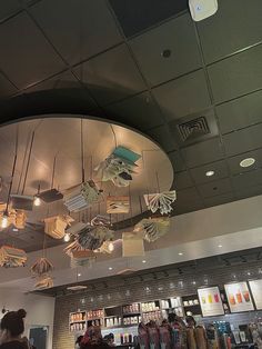 people are standing around in a store with umbrellas hanging from the ceiling above them