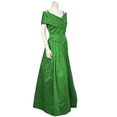 For Sale on 1stDibs - Dramatic 1980's emerald green satin gown by Arnold Scaasi. The dress has a pleated off the shoulder detail that wraps around the front bust. The asymmetrical Green Satin Gown, Arnold Scaasi, Mother Of The Bride Dresses Long, Under The Skirt, Formal Outfits, Satin Gown, Fall Skirts, Green Satin, Formal Outfit