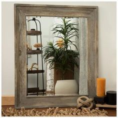 a mirror sitting on top of a table next to a potted plant and candle