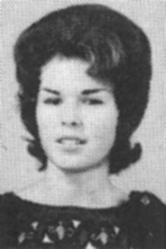 an old black and white photo of a young woman with short hair wearing a dress