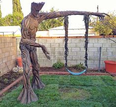 a statue of a man swinging on a swing set in a yard with a brick wall behind it