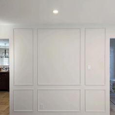 an empty room with white walls and tile flooring in the center is seen from across the room