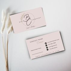 two business cards sitting next to each other on top of a white surface with dry grass