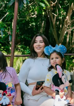 a woman and two children sitting on a bench with stuffed animals in front of them