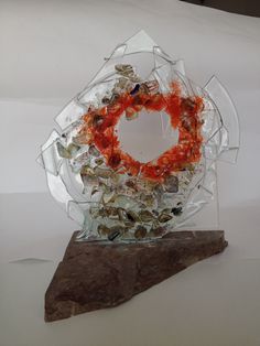 a piece of art that has been made out of glass and is sitting on top of a rock