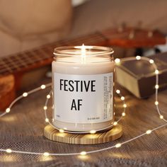 a white candle sitting on top of a wooden table next to a string of lights