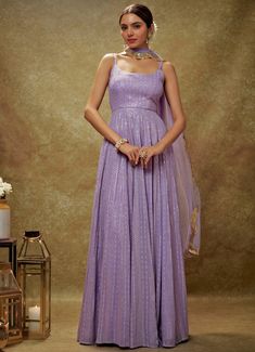 Embrace timeless elegance with the Lavender and Gold Sequin Embroidered Anarkali Gown, expertly crafted from luxurious viscose georgette. This lavender gown is adorned with intricate sequin and threadwork embroidery, bringing a touch of opulence to its design. The flattering strappy round neckline and chic back cutout at the waist introduce a modern flair to the traditional silhouette. Its flowy, floor-length design exudes regal charm, perfectly complemented by the matching net dupatta with delicately embroidered scallop lace. Ideal for Mehndi, Sangeet, or as wedding guest attire, this ensemble seamlessly blends classic allure with contemporary sophistication Composition : Anarkali - Viscose Georgette and Dupatta - Soft net Care: Dry Clean Only and Vacuum Storage This product can be custom Sequin Anarkali, Threadwork Embroidery, Bridal Crop Top, Lavender Gown, Kurta Lehenga, Waistcoat Woman, Embroidered Anarkali, Indian Wedding Wear, Anarkali Gown