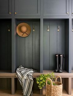 a coat rack with two coats and a hat on it next to a plant in a basket