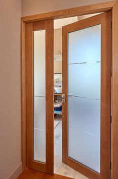 an open wooden door with frosted glass on the front and back doors, in a house