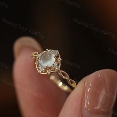 a woman's hand holding an engagement ring with a white stone in the middle