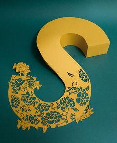 the letter s is cut out from paper and placed on a blue surface with flowers