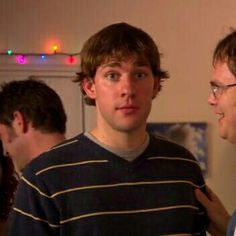 two young men standing next to each other in a room with christmas lights on the walls