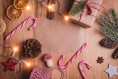 christmas decorations and presents laid out on a wooden table with wrapping paper, candy canes, pine cones, orange slices, star shaped candies