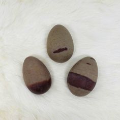 three brown rocks sitting on top of a white fur covered floor next to each other