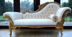 a white and gold couch sitting in front of a window