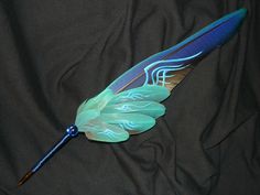 a blue and green feather laying on top of a black cloth