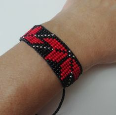 a person wearing a red and black beaded bracelet