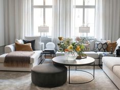 a living room filled with lots of furniture and flowers on top of a coffee table