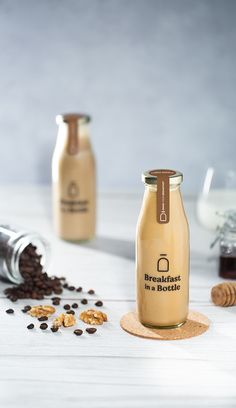 two glass jars filled with coffee beans next to some other items on a white table