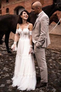 a man and woman standing next to each other in front of horses