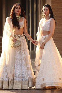 two women in white outfits holding hands