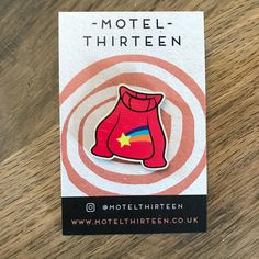 a pin badge depicting a red boxing glove on a wooden table with the words motel thirteen