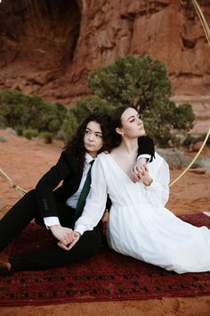 two people sitting on a rug in the desert