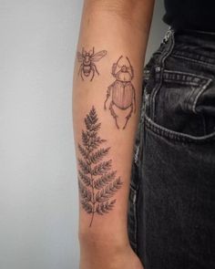 a woman's arm with tattoos on it and two bugs in the middle of her arm