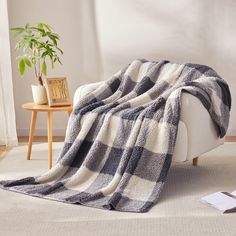 a living room with a white couch and black and white plaid blanket on top of it